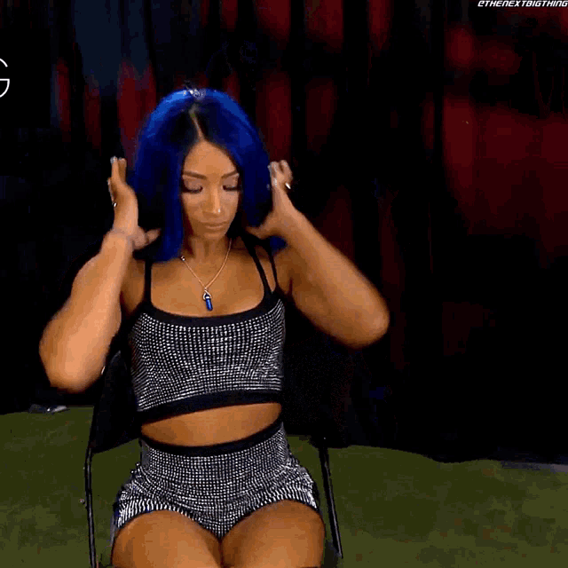a woman with blue hair is adjusting her hair