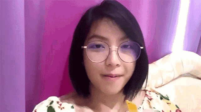 a young girl wearing glasses is sitting on a bed .