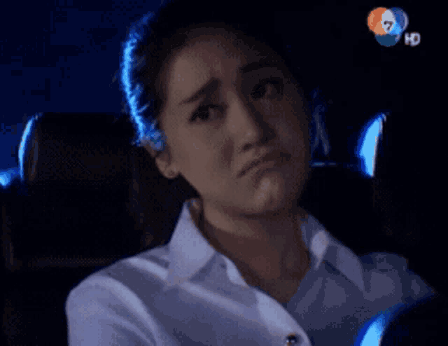 a woman in a white shirt is sitting in a car with a hd logo on the bottom right