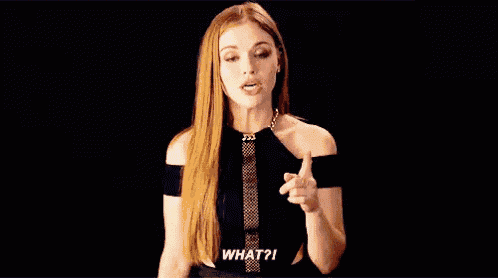 a woman with long red hair is talking and pointing at something .