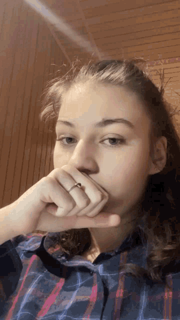 a girl with a ring on her finger is covering her mouth with her hand