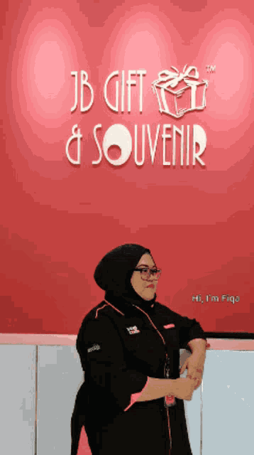 a woman stands in front of a jb gift and souvenir sign