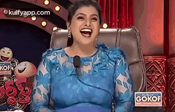 a woman in a blue dress is sitting in a chair and laughing .