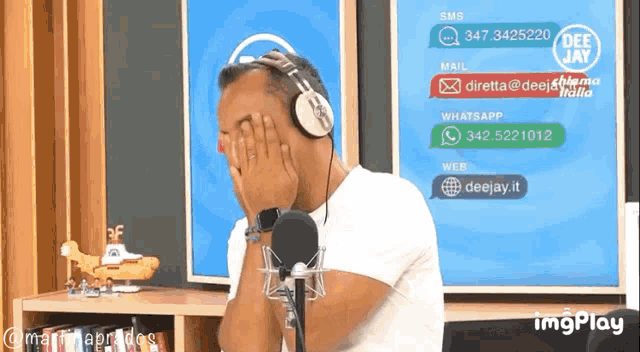 a man wearing headphones is covering his face in front of a screen that says deejay.it