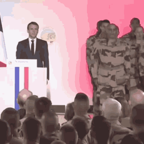 a man in a suit and tie stands at a podium with a sign that says ' s. dumas '