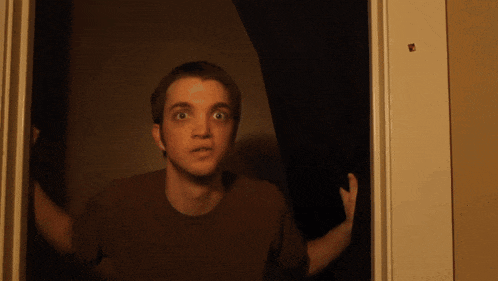 a man in a brown shirt is looking out a window