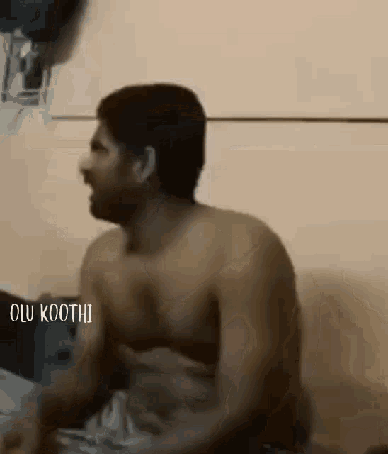 a shirtless man is sitting on a bed and talking to another man .