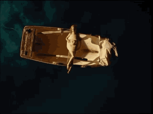 a naked woman is laying on the back of a boat in the ocean