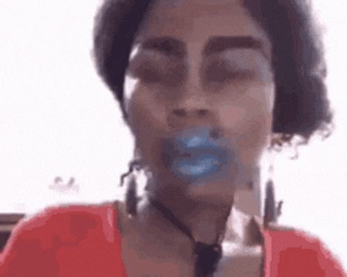 a woman with blue lips and earrings is making a funny face with her eyes closed .