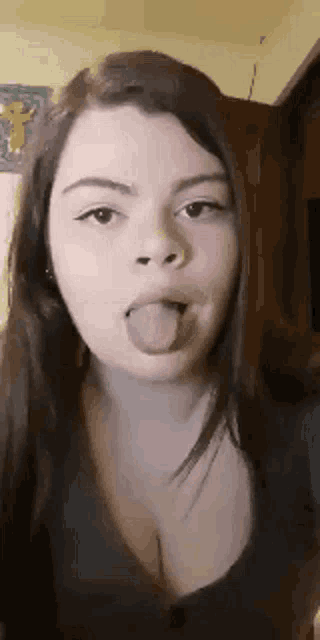 a young woman is sticking her tongue out in a room .