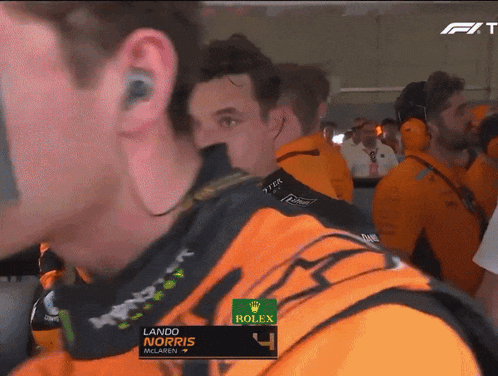 lando norris is wearing an orange shirt with rolex on it