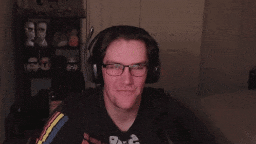 a man wearing headphones and a t-shirt with the word raw on it is laughing and waving his hand .