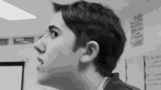 a black and white photo of a young man making a funny face .