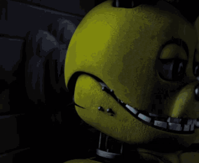 a yellow stuffed animal with a blue eye is smiling