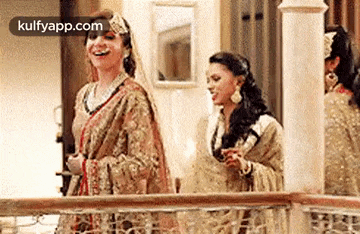 two women in traditional clothing are standing next to each other on a balcony .