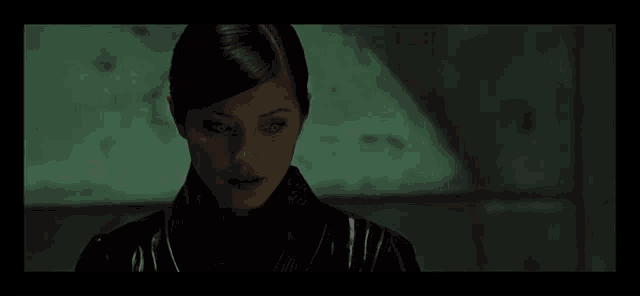 a woman in a black jacket is looking at the camera