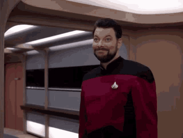a man with a beard wearing a red uniform with a star trek badge