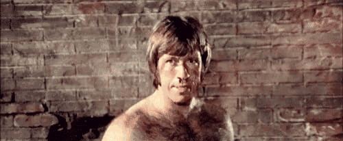 a man without a shirt is standing in front of a brick wall