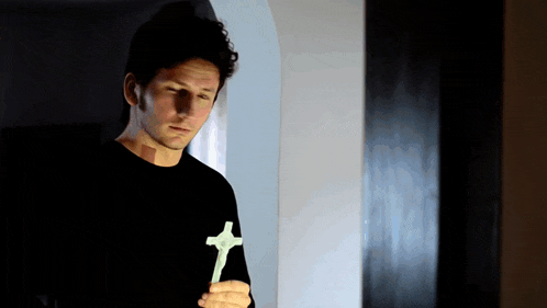 a man in a black shirt is holding a white cross