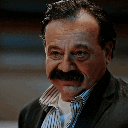 a man with a mustache is wearing a suit