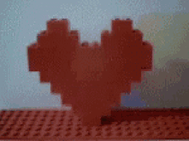 a heart made out of lego bricks is sitting on a red surface