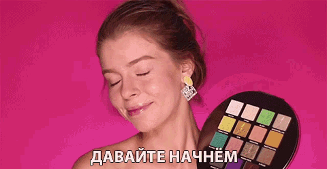 a woman is holding a palette of eye shadows in front of her face with a pink background and russian writing