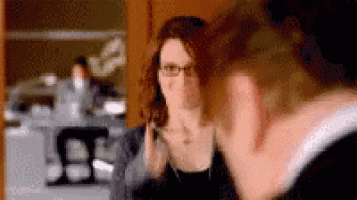 a woman with glasses is looking at herself in the mirror .