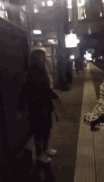 a woman is walking down a sidewalk at night in a city .