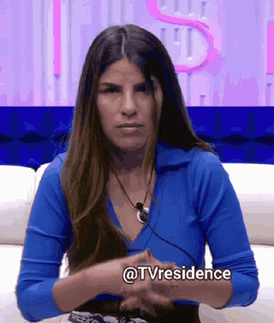 a woman in a blue shirt is sitting on a couch with her hands folded and the words @tvresidence written on the bottom right