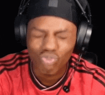 a man wearing headphones and a red shirt is making a face .