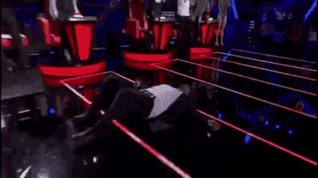 a man is laying on his stomach on a stage while a woman holds his chest .