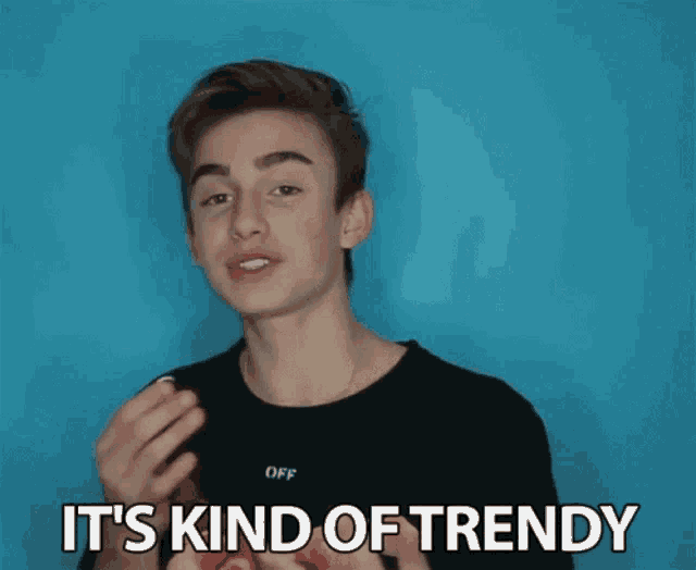 a young man in a black shirt says it 's kind of trendy in front of a blue background
