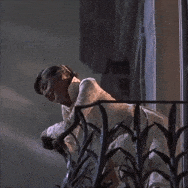 a woman standing on a balcony holding a rose
