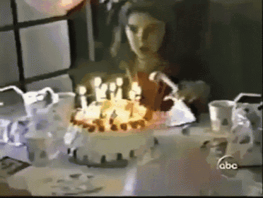 a woman is blowing out candles on a birthday cake with the abc logo in the background