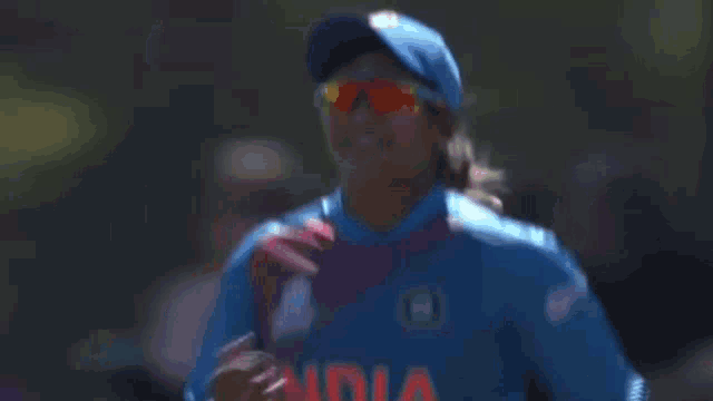 a woman wearing sunglasses and a blue hat has the number 71 on her back