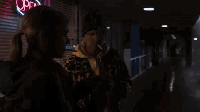 a man and a woman are standing next to each other in a dark hallway looking at a painting .