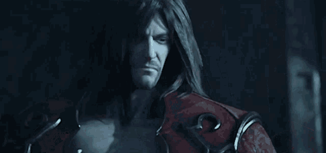 a man with long hair and a beard is standing in a dark room in a video game .