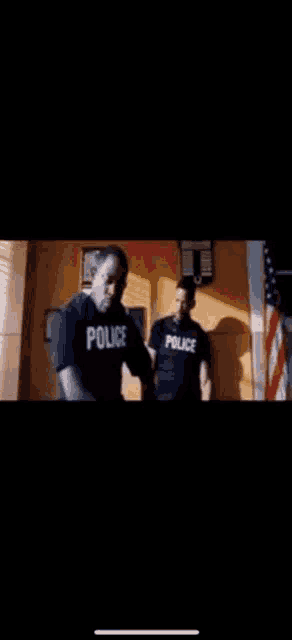 two police officers are standing next to each other in a dark room .