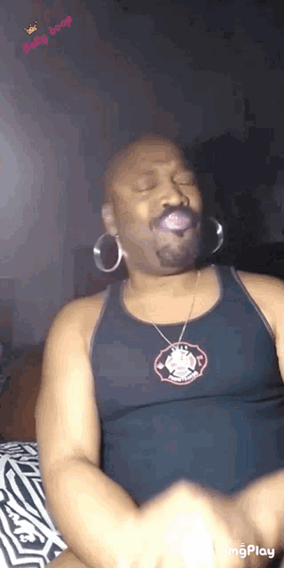 a man wearing a tank top and a necklace with a devil on it