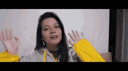 a woman wearing a yellow jacket is making a funny face .