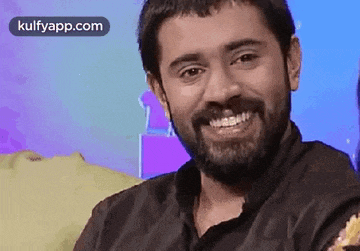 a man with a beard is smiling and holding a piece of food in his hand .