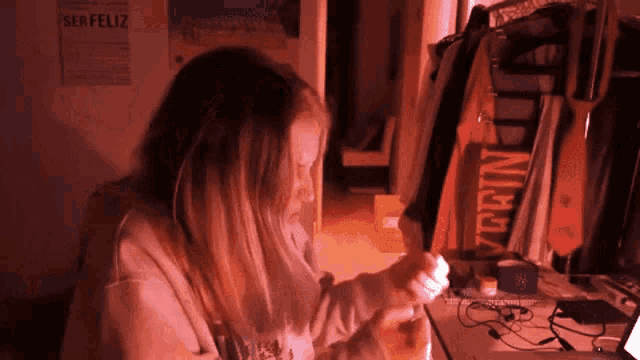 a girl sitting at a desk with a poster on the wall that says serfeliz