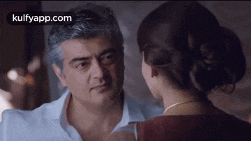 a man and a woman are looking at each other in a dark room .