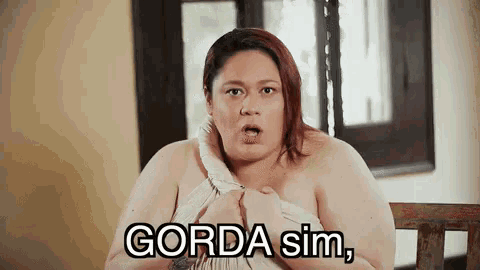 a naked woman is sitting on a wooden bench with the words gorda sim written on her chest .