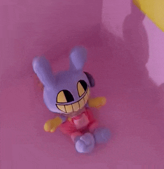 a purple stuffed animal is sitting on a pink surface .