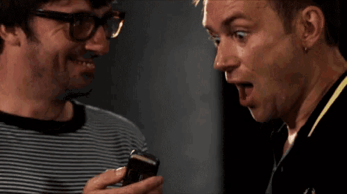 a man with glasses looks surprised at another man