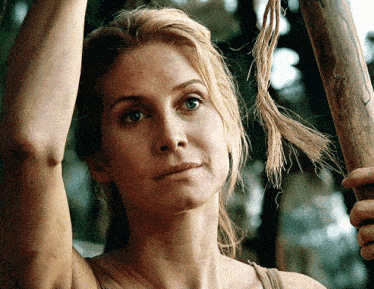 a woman with blonde hair is holding a wooden pole
