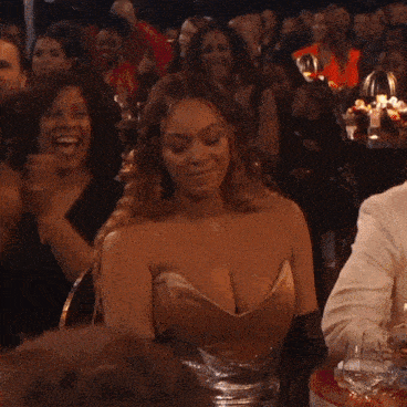 a man in a white suit and a woman in a brown dress are dancing in a dark room
