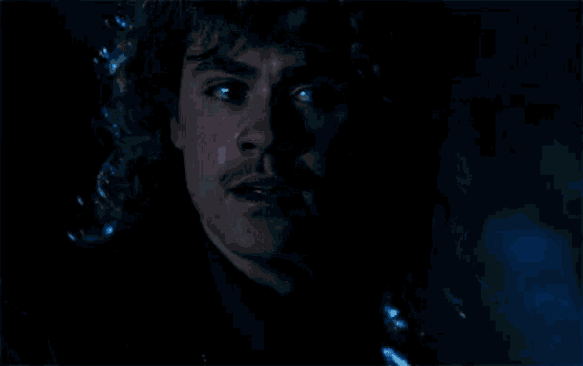 a close up of a man 's face in the dark with tears coming out of his eyes .