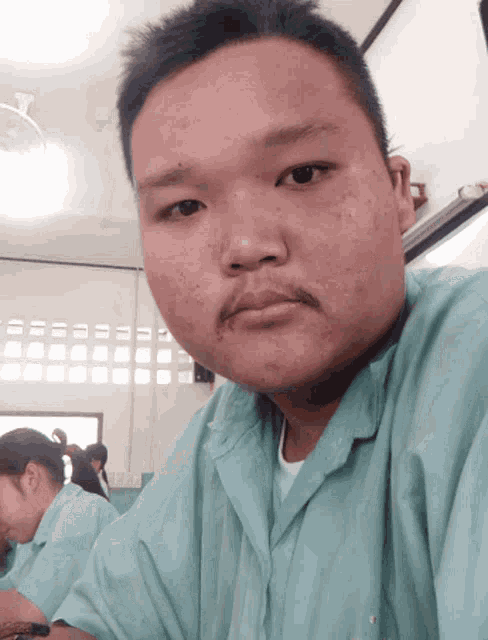 a man with a mustache looks at the camera in a room